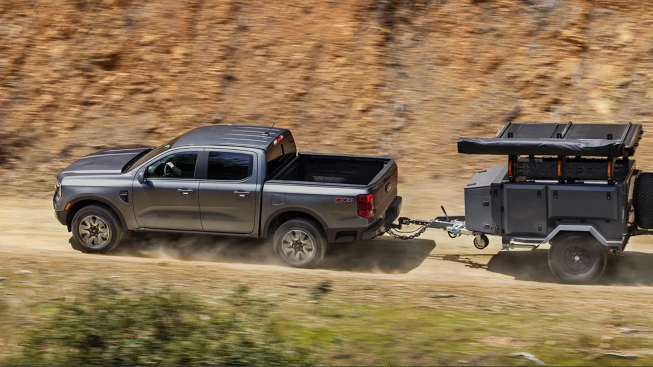 Ford Ranger 2026 gris remorquant une remorque de camping hors route dans un paysage naturel, illustrant sa capacité de charge utilitaire