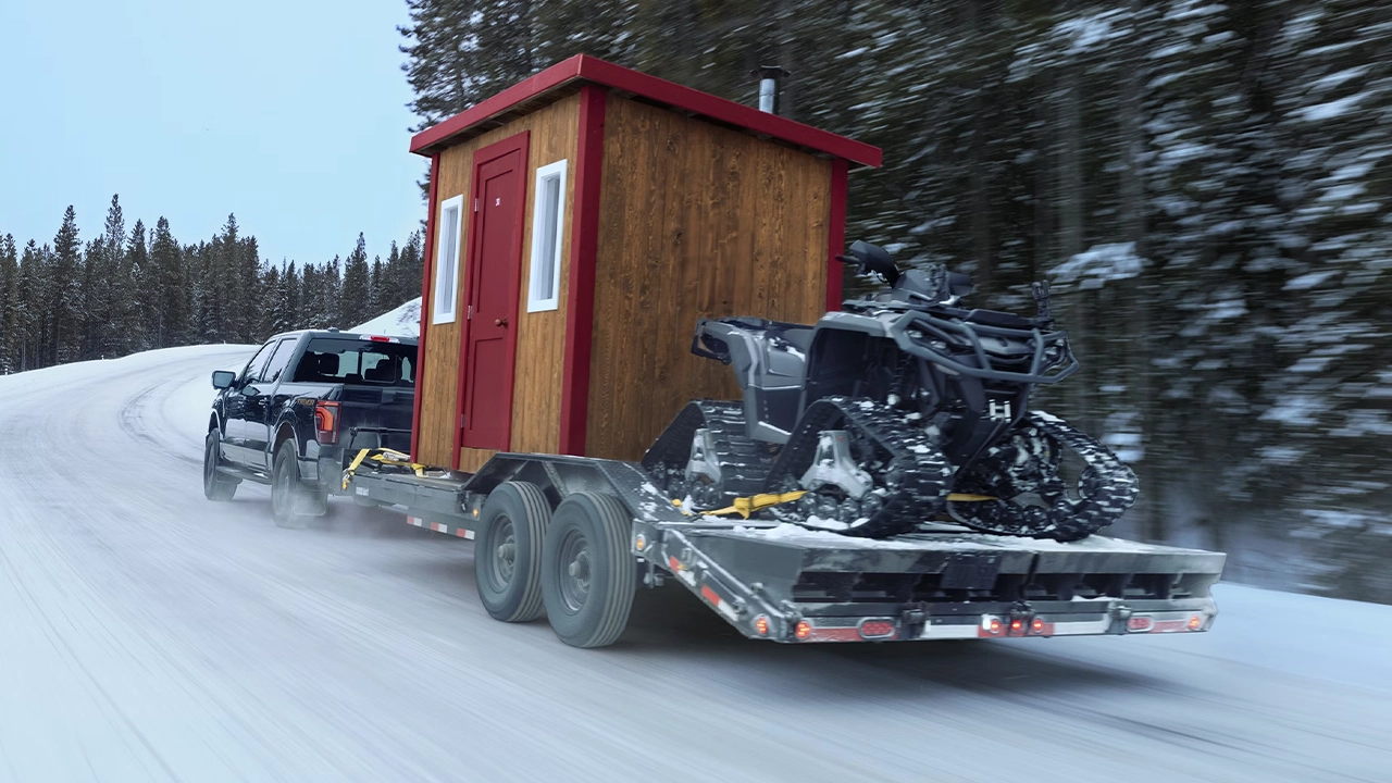Vue arrière du Ford F-150 sur route de neige tirant un cabanon et un vtt