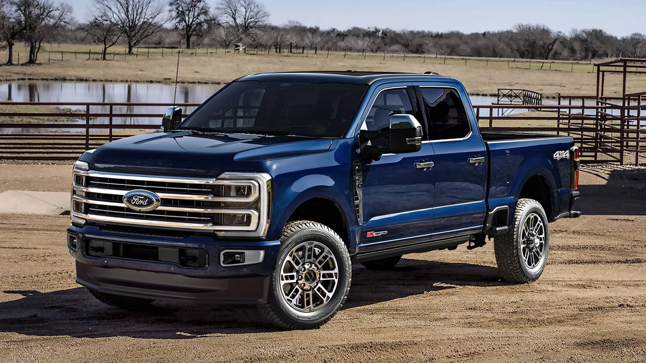 Ford F-350 Super Duty bleu marine 4x4 stationné sur un chemin de terre dans un ranch, près d'un étang.