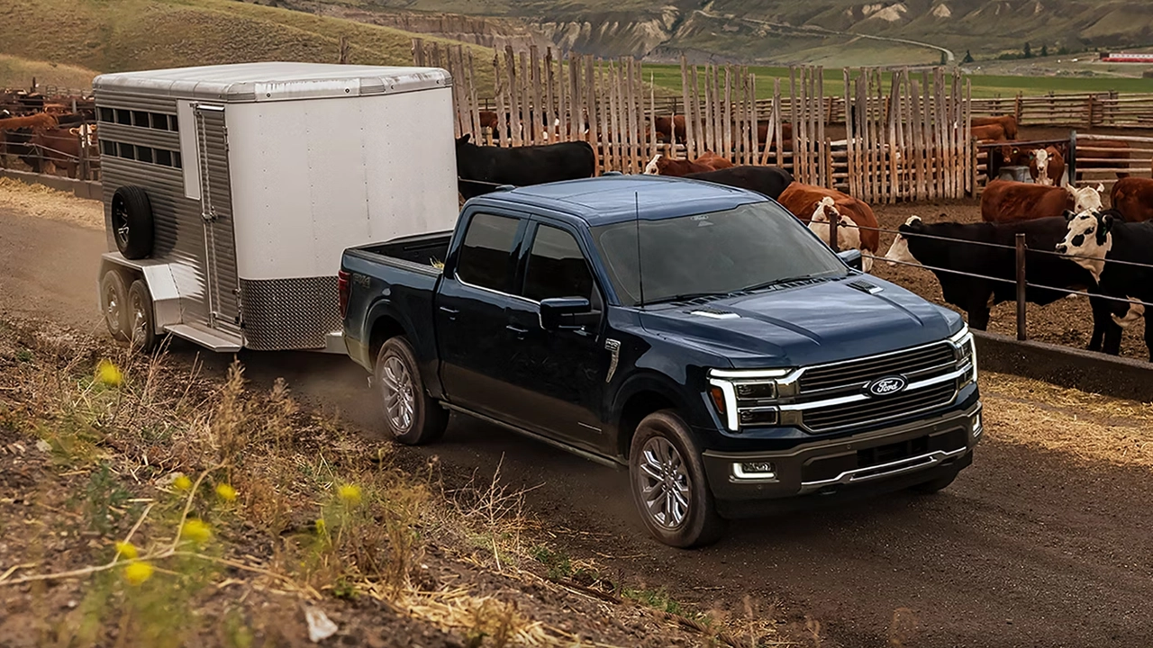 Ford F-150 2026 bleu remorquant une remorque près d'un ranch.