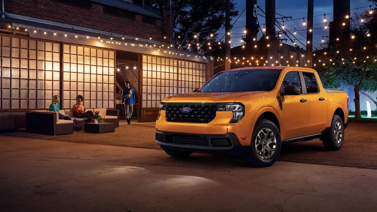 Ford Maverick 2026 orange garé devant une terrasse illuminée la nuit.