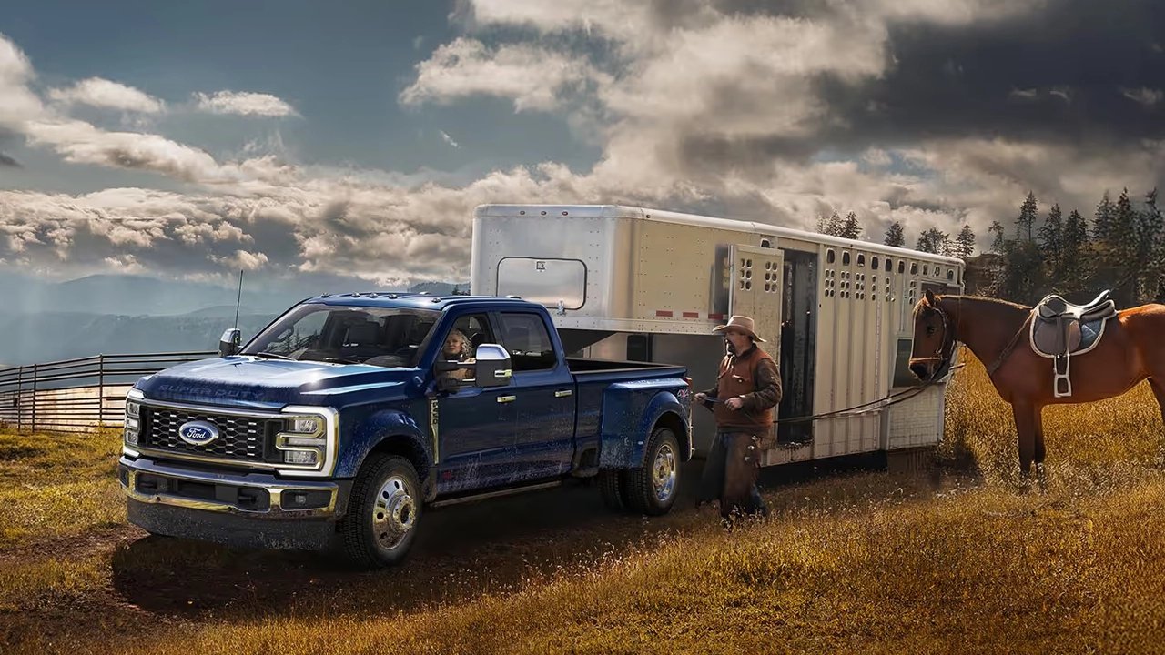 Ford F-450 Super Duty bleu remorquant un van à chevaux en ranch.