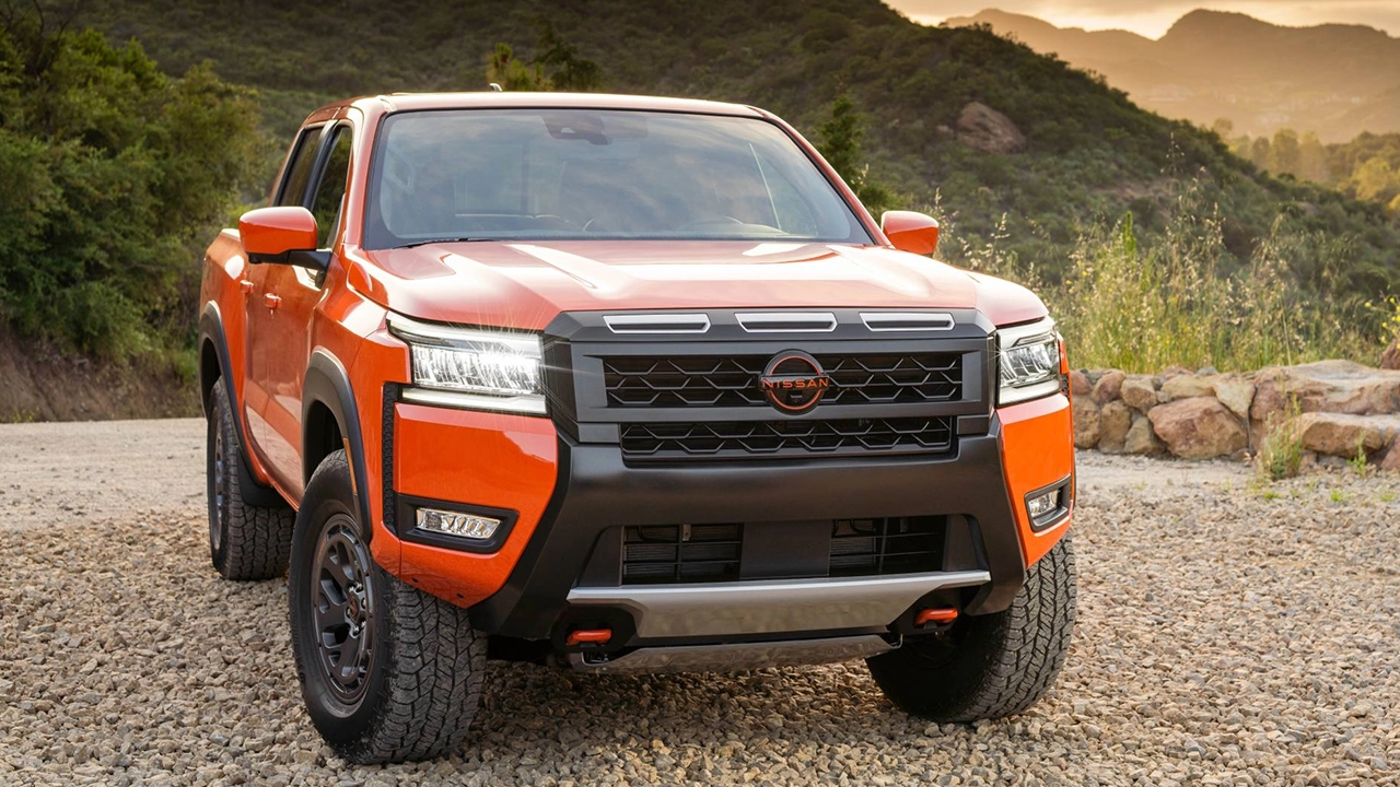 Nissan Frontier 2026 orange vif garé sur gravier face aux montagnes.